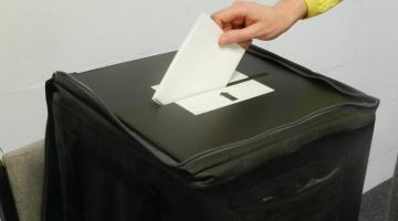 Hand putting ballot paper into ballot box