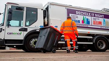 Recycling truck parked with bin man taking bin to it