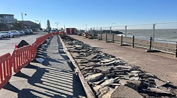 Orange barriers next to pavement and railings on seafront